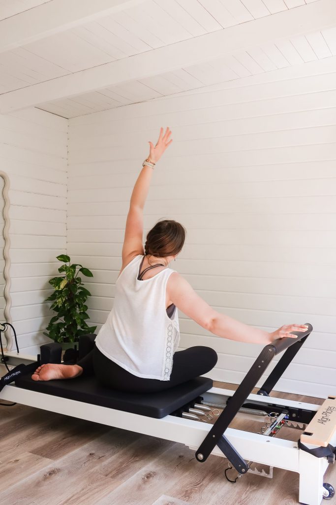 A Pilates instructor demonstrating an exercise on a reformer