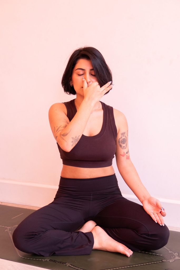 A yoga teacher demonstrating a seated breathing exercise
