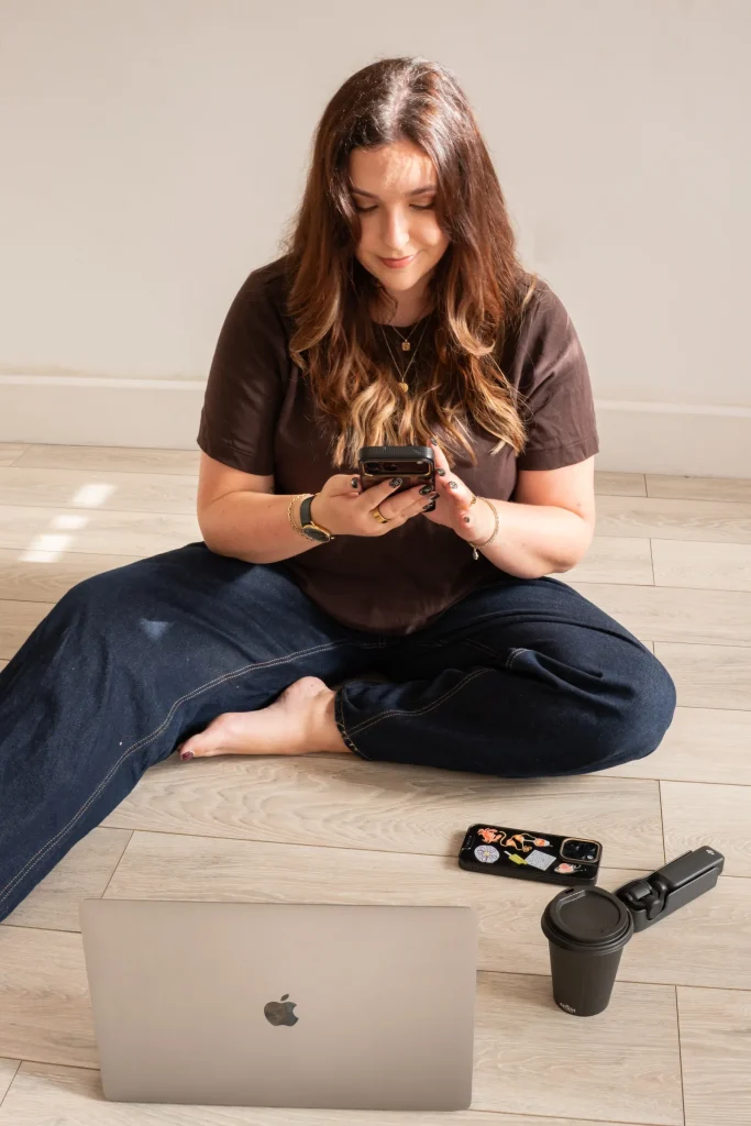 Jaye sitting with her phone, laptop and filming equipment