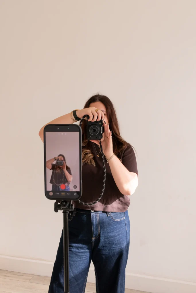 Jaye taking a photograph while a phone records the shoot