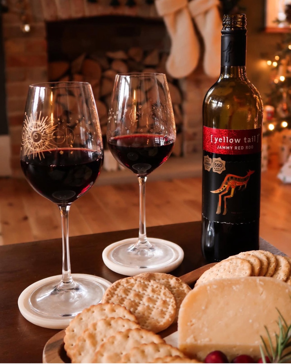 Yellow Tail Jammy Red Roo beside two glasses of wine and a cheeseboard
