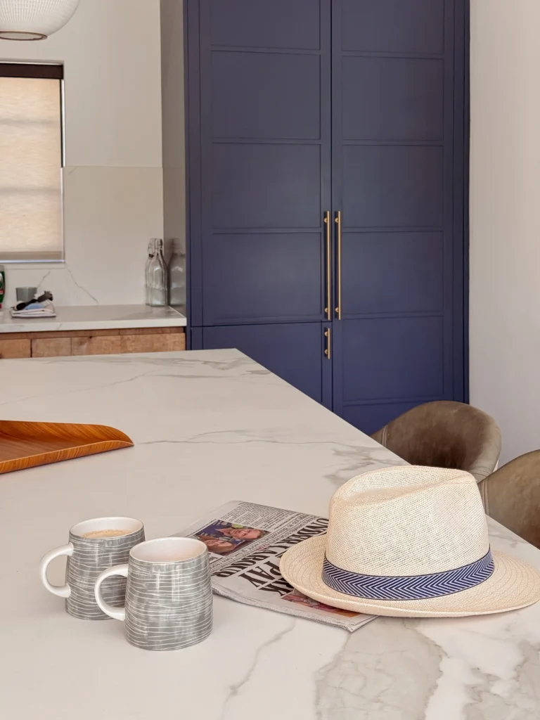 Marble kitchen island with coffee mugs, a newspaper and a hat