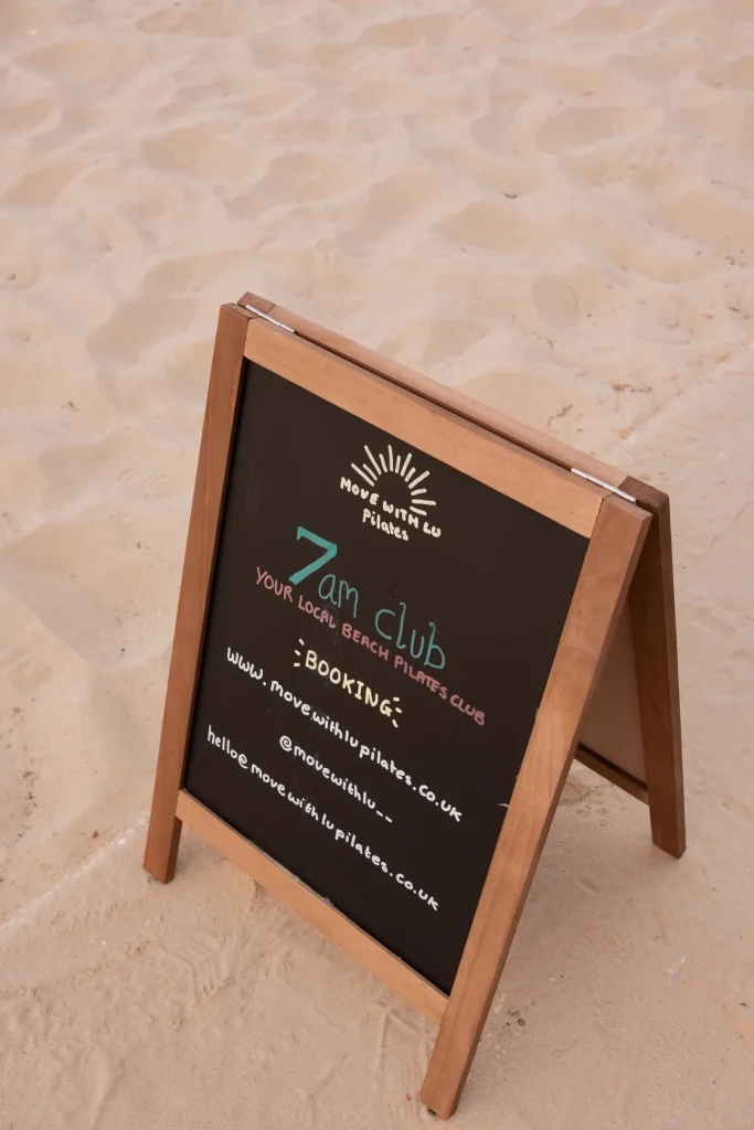 Move with Lu Pilates sign on the beach