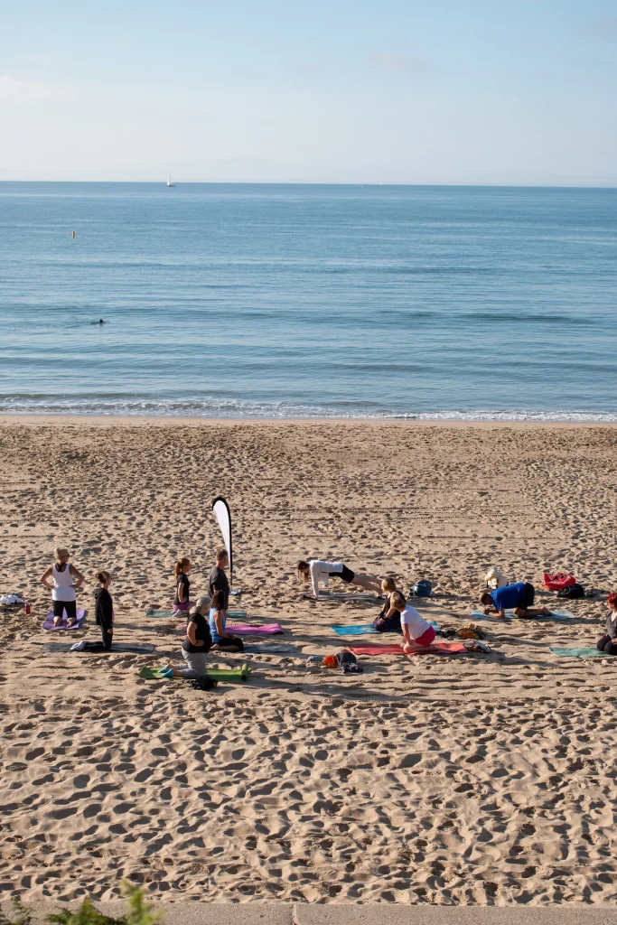 Beach Pilates class on mats beside the water