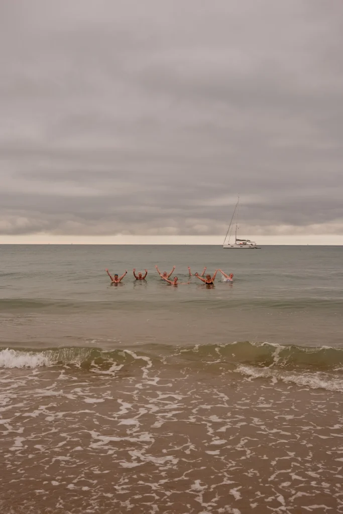 Group in the sea raising their arms after a beach Pilates session