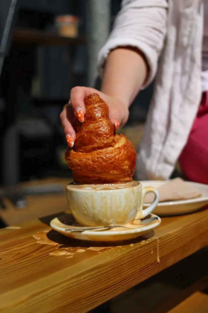 Hand dipping a croissant into a cup of coffee
