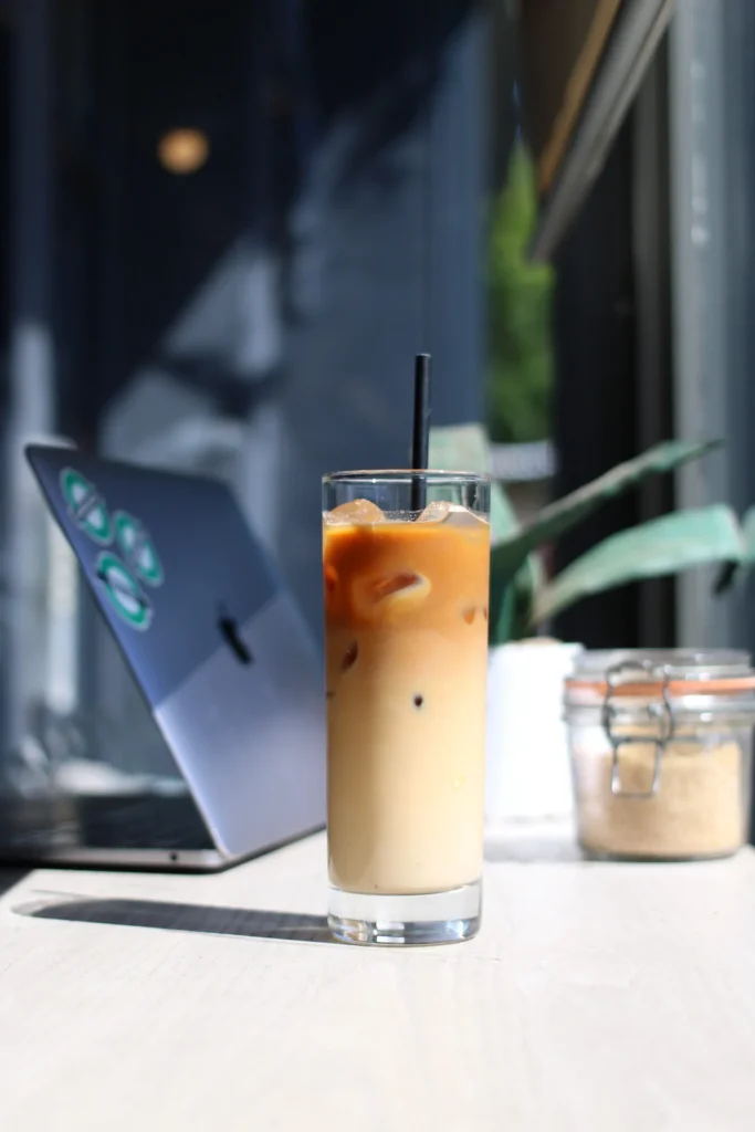 Iced coffee on a table beside a laptop