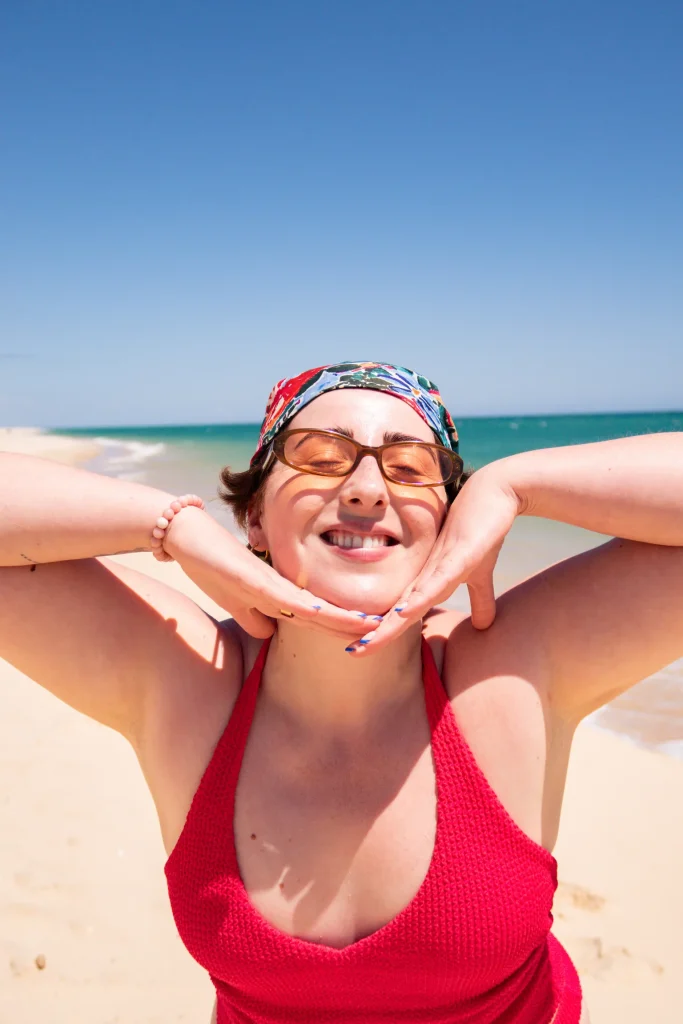 Smiling person in a red top posing at the beach