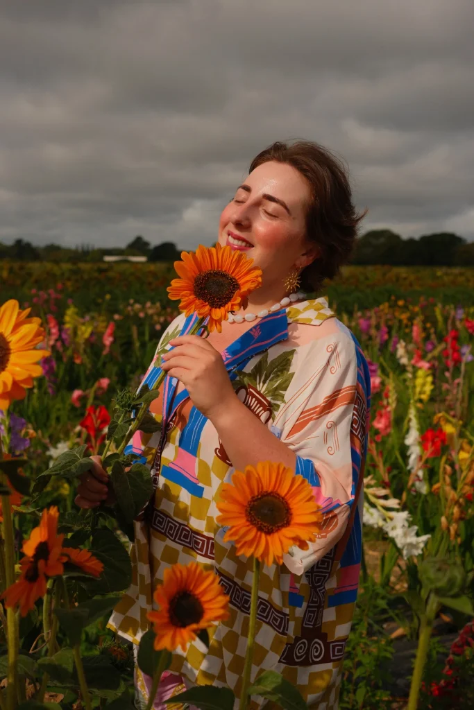 Person holding an orange flower in a flower field