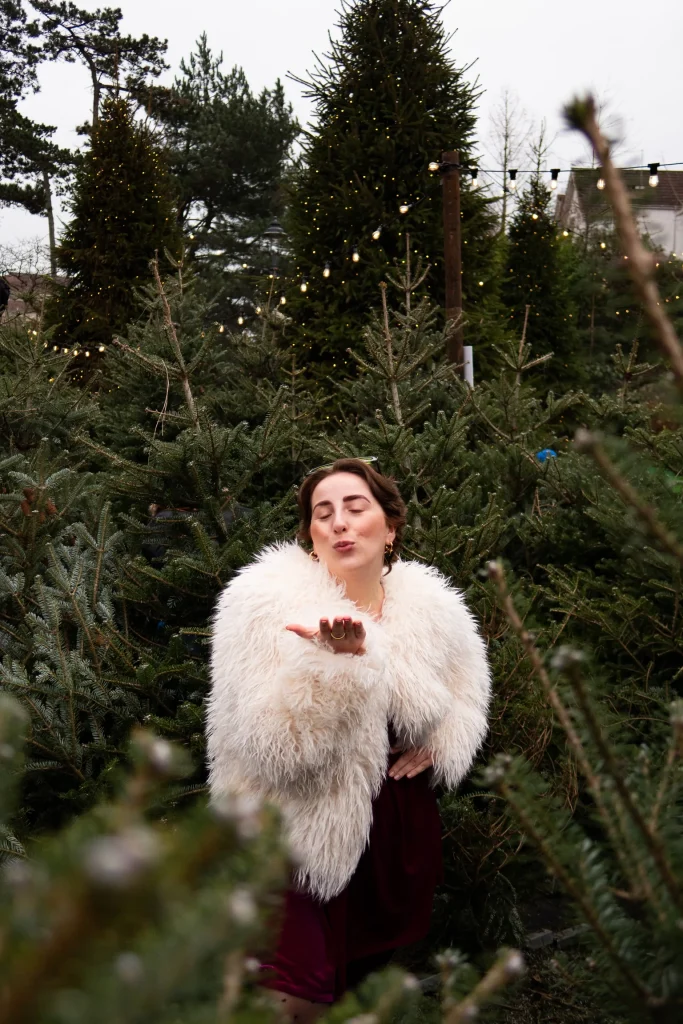 Person blowing a kiss among Christmas trees