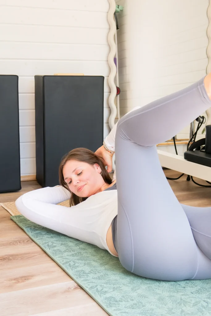 Pilates instructor stretching on a mat with one leg raised