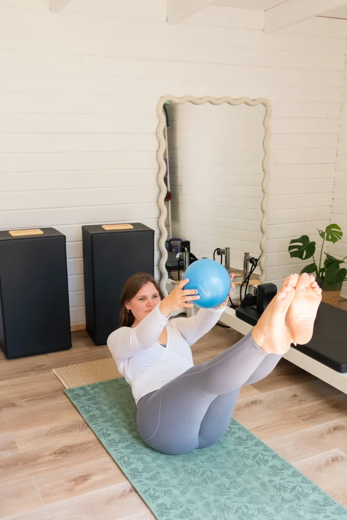 Pilates instructor balancing with a blue exercise ball