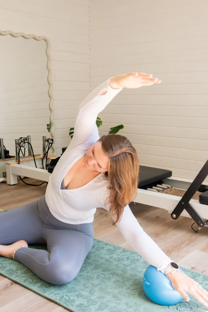 Pilates instructor stretching sideways with an exercise ball