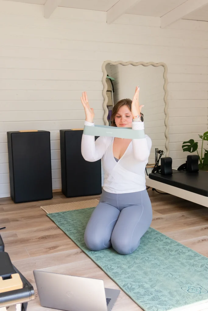 Pilates instructor using a resistance band while kneeling