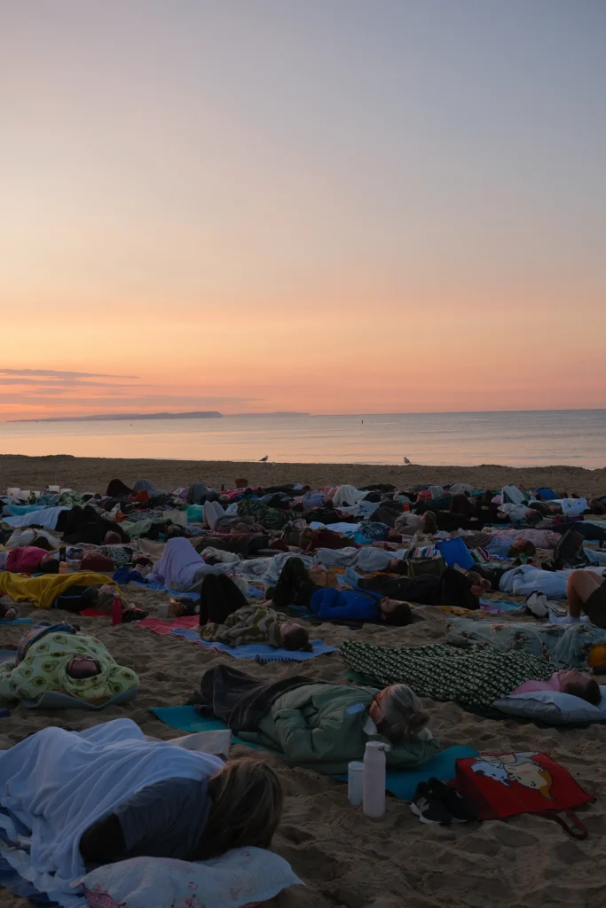 Participants lying on the beach beside the sea at sunrise