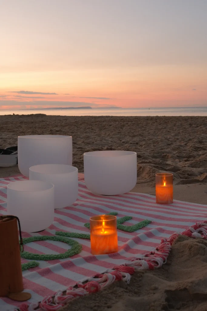 Singing bowls and candles on the beach at sunrise