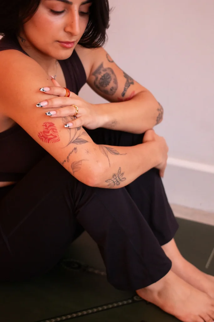Person seated on a yoga mat with arms resting on their knees