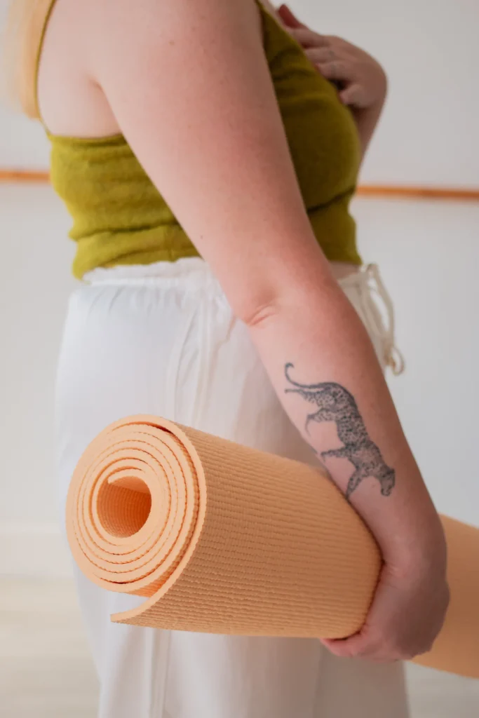 Person holding a rolled yoga mat