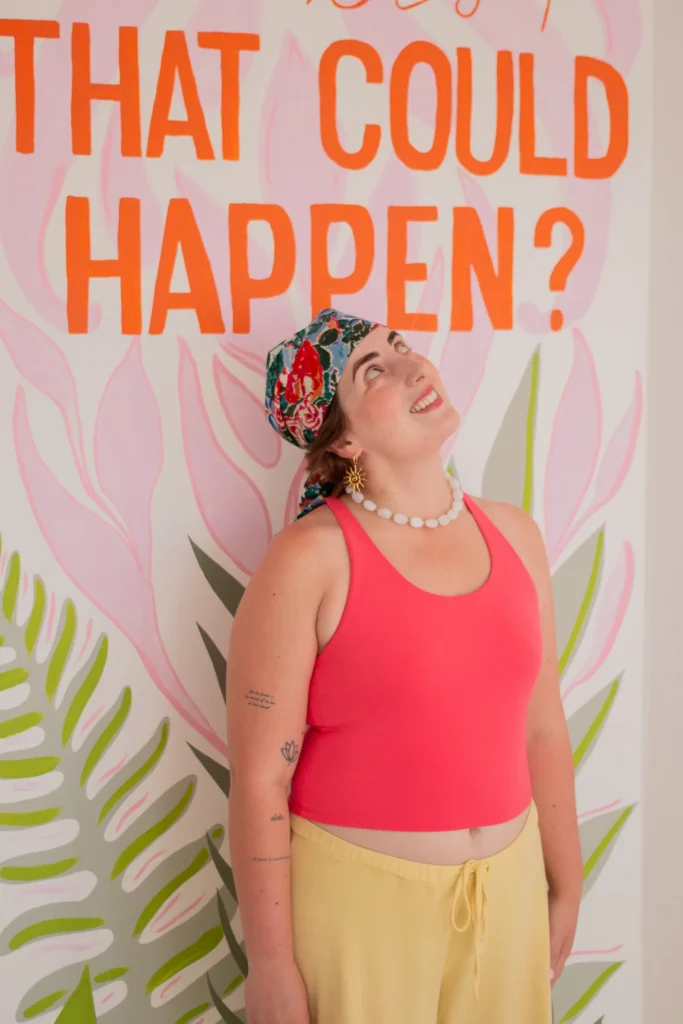 Woman standing before a colourful studio mural